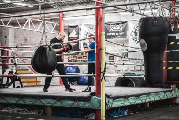 Gavin holding a heavy bag in the ring while a client trains at Barum Boxing Club
